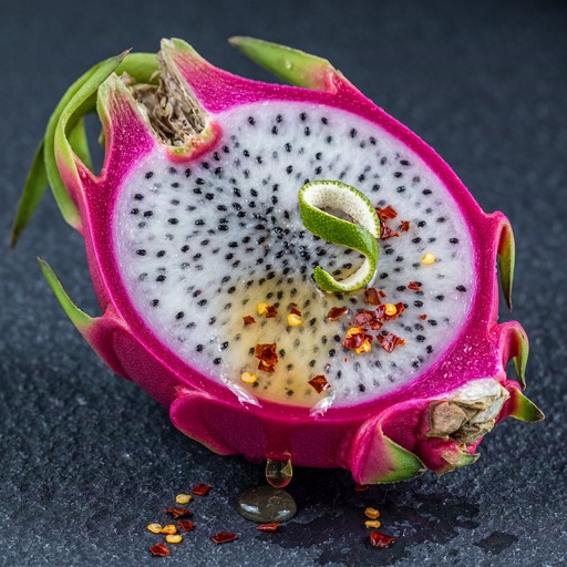 A halved pink dragon fruit with white, seed-speckled flesh, red chili ...