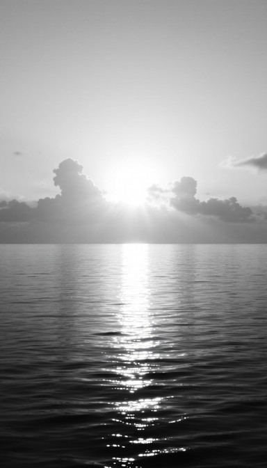 Gentle waves reflect brilliant sunlight breaking through clouds over ...