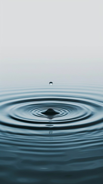 A single water droplet falls gracefully, creating concentric ripples ...