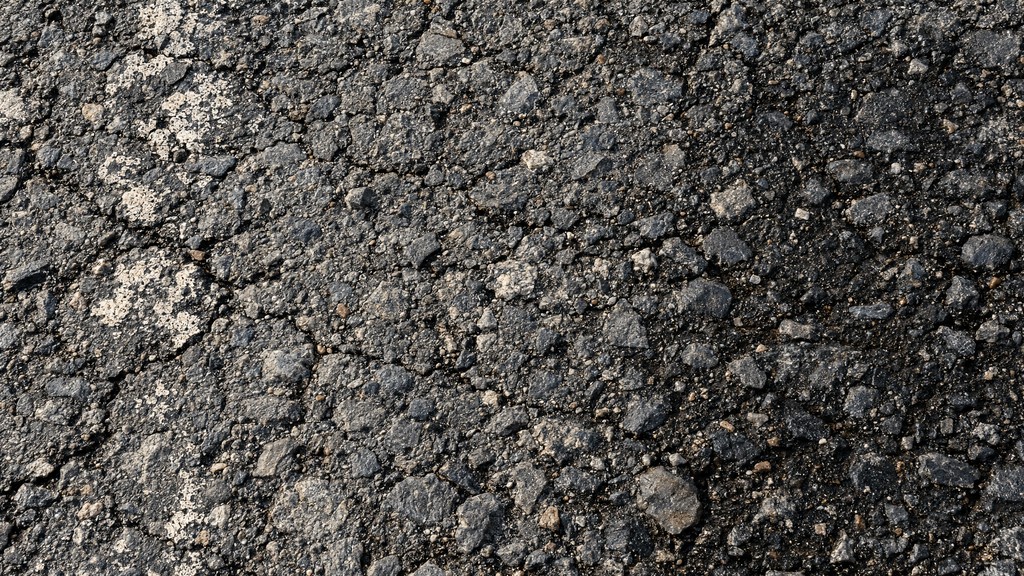 A close-up view of old, weathered asphalt fills the whole frame with a ...